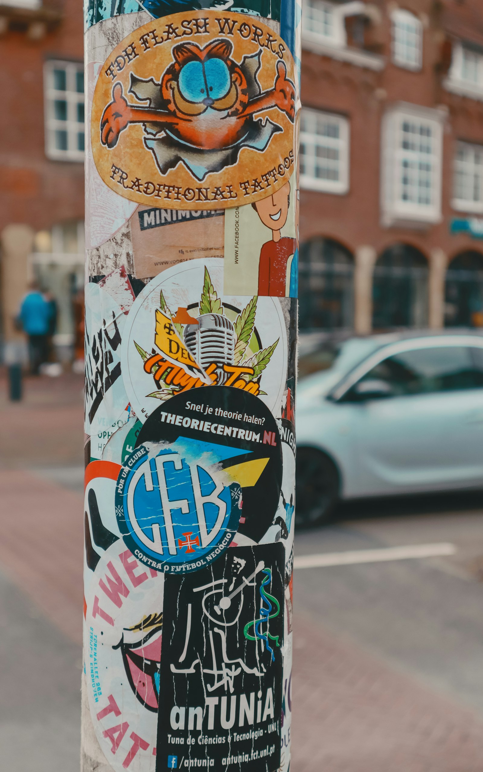 A public pole covered in illegal stickers and posters